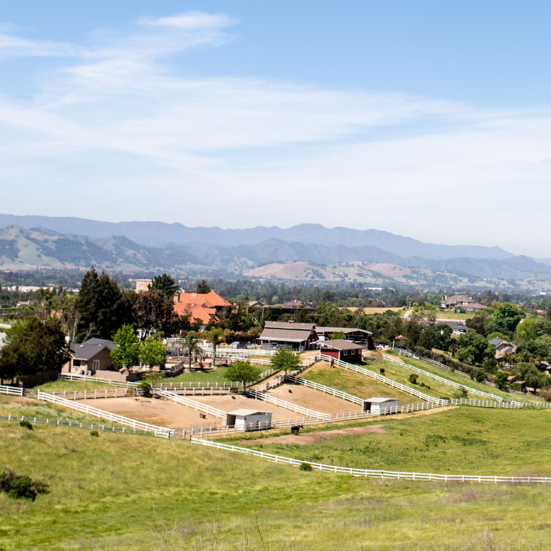 Rural community with fencing and ranch homes on green hills.